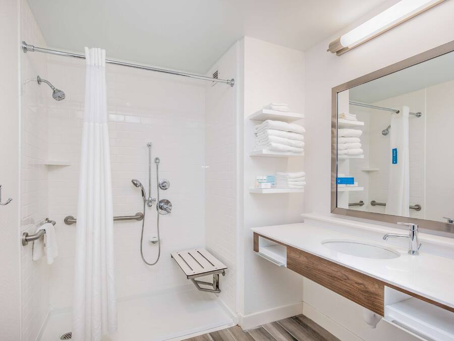 A modern bathroom with a glass shower enclosure, a white sink, and a large mirror.