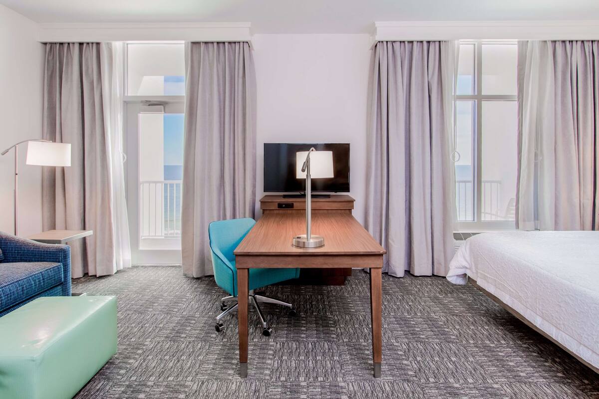 Een hotelkamer met een bed, een bureau met lamp, een stoel en een televisie.