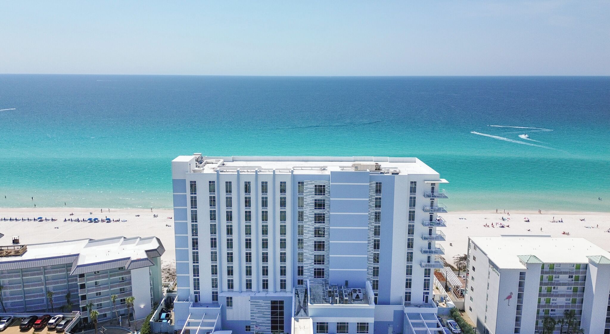 Ein Hochhotel mit mehreren Stockwerken, Blick auf den Strand und einem Poolbereich.