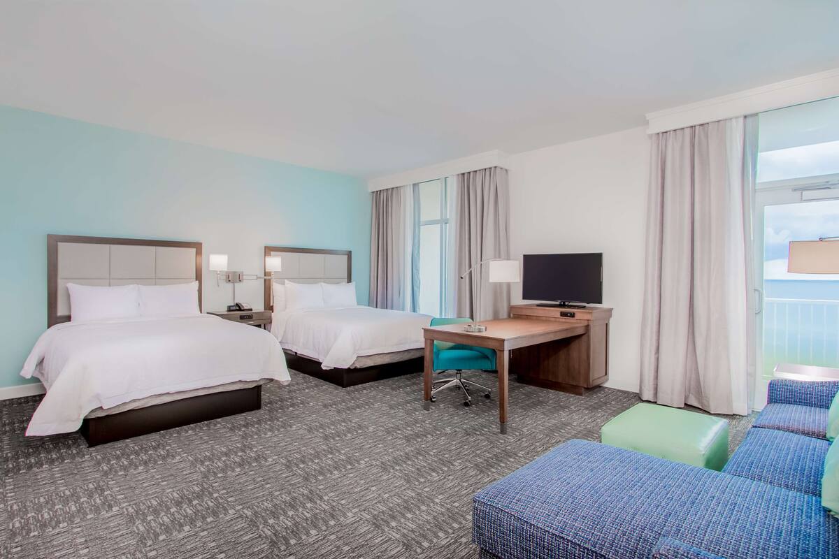 Een hotelkamer met twee bedden, een bureau, een televisie en een zithoek.