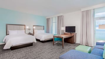 Habitación de hotel con dos camas, un escritorio, un televisor y una zona de estar.