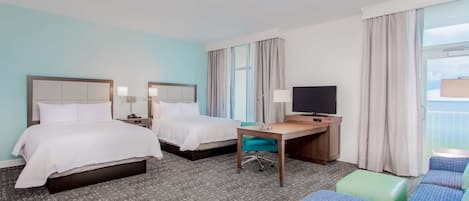 Habitación de hotel con dos camas, un escritorio, un televisor y una zona de estar.