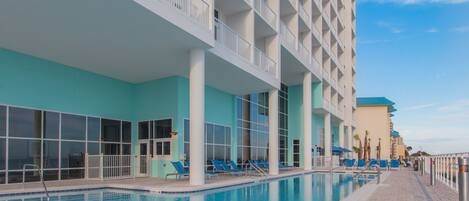 A hotel with a swimming pool, outdoor seating, and a modern architectural design.
