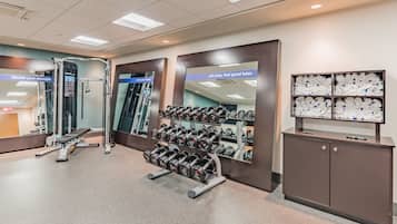 A gym with weight racks, benches, and a mirror.