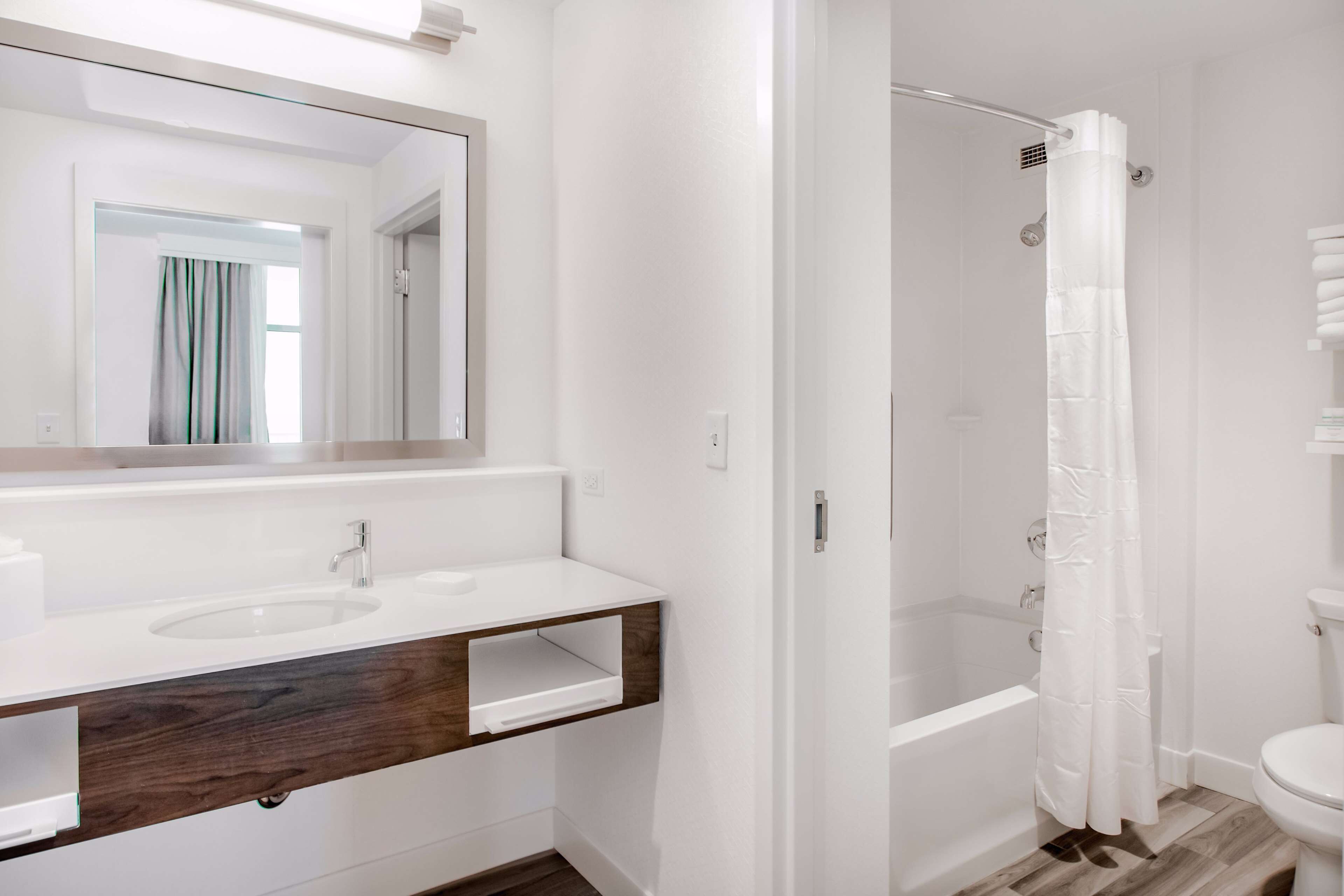 A bathroom with a white sink, mirror, and shower curtain.