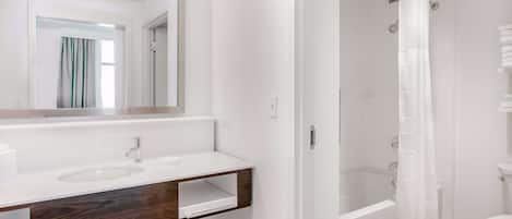 A bathroom with a white sink, mirror, and shower curtain.
