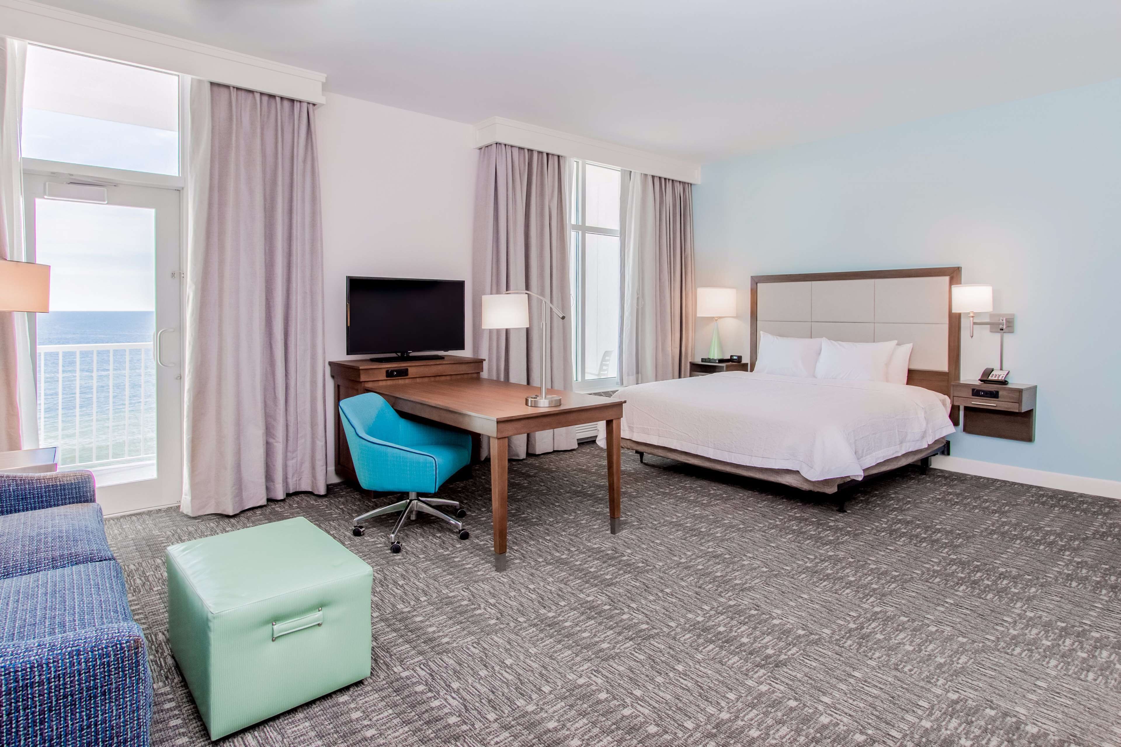 A hotel room with a bed, desk, chair, and a television.