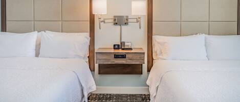 Habitación de hotel con dos camas, una mesita de noche con lámpara y teléfono.