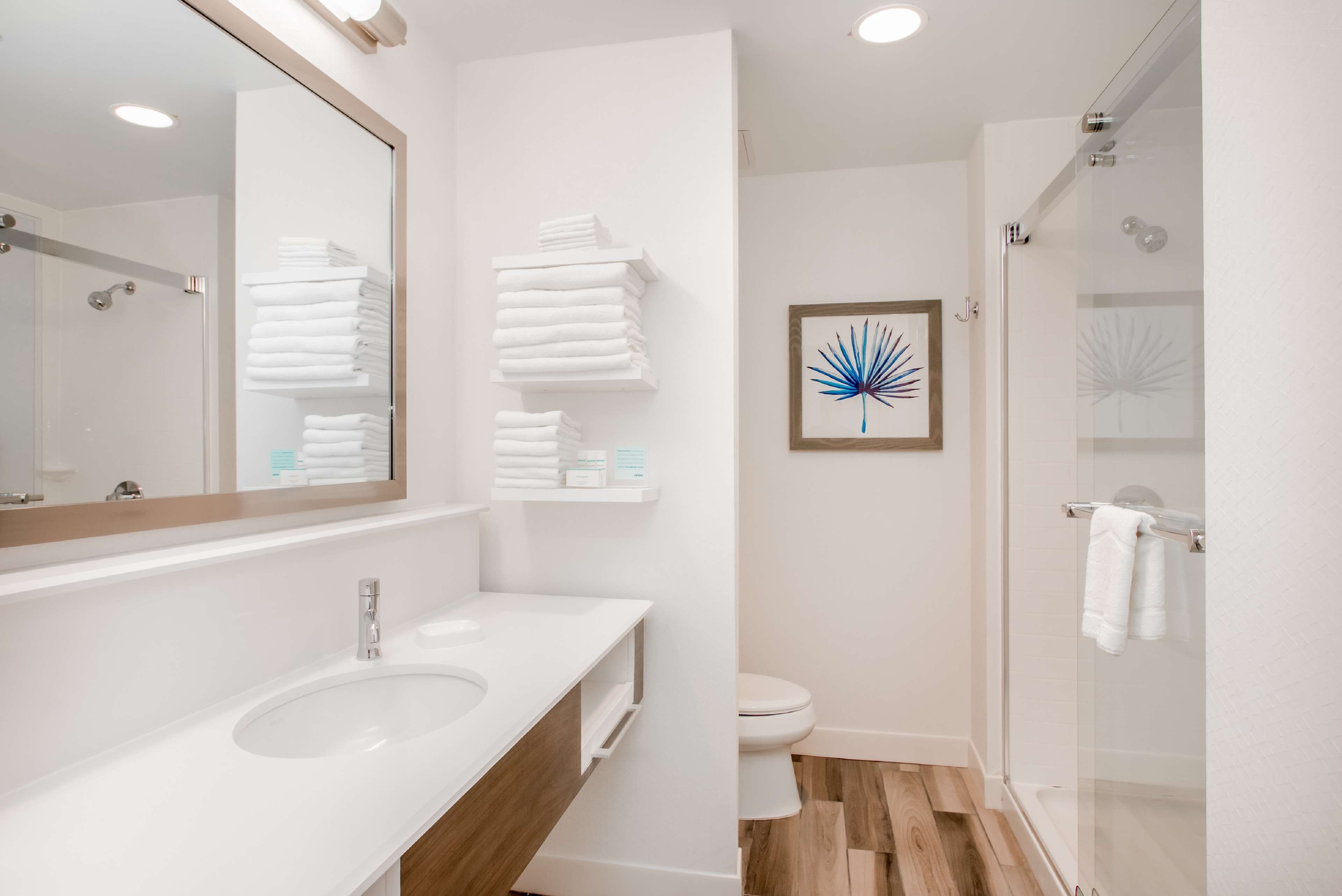 A modern bathroom with a white sink, mirror, and glass shower enclosure.