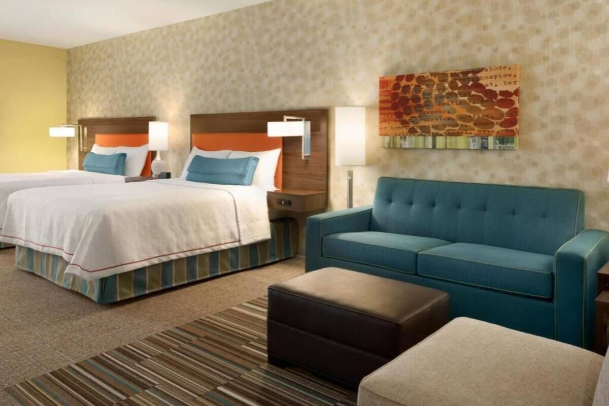 Une chambre d’hôtel avec deux lits, un canapé et un tableau au mur.