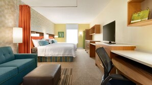 Une chambre d’hôtel comprenant un lit, un bureau, une chaise, un canapé et un téléviseur.