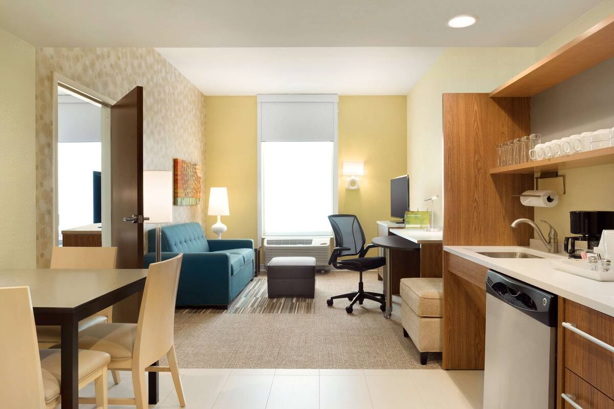 Une chambre d’hôtel compacte comprenant un coin repas, une kitchenette et un canapé.