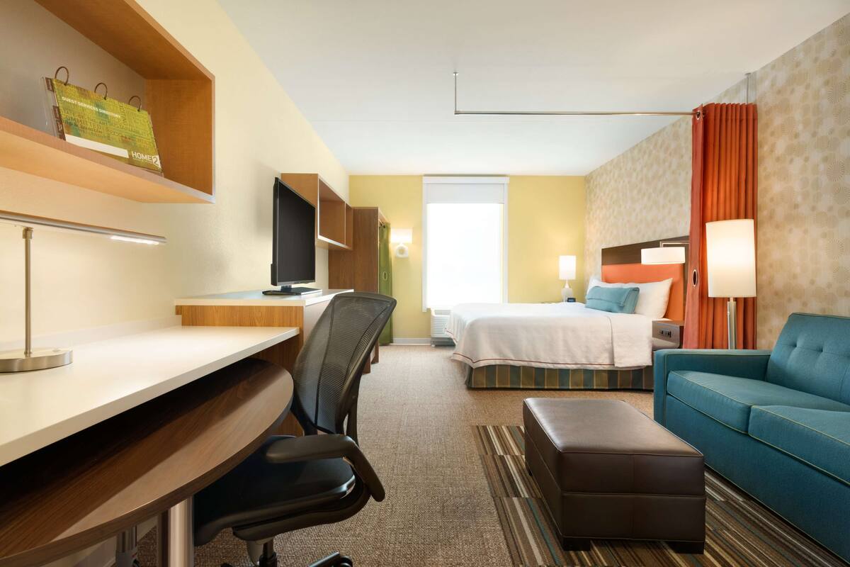 Une chambre d’hôtel équipée d’un bureau, d’une chaise, d’un lit et d’un canapé.