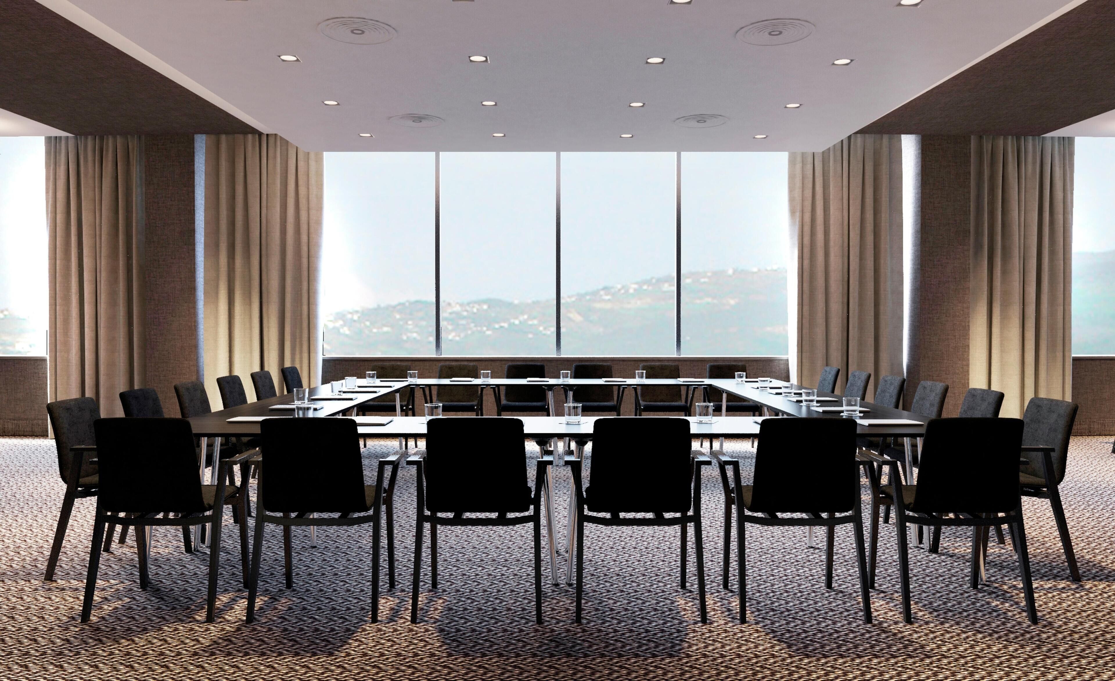 A conference room with a long table, chairs, and large windows offering a view.
