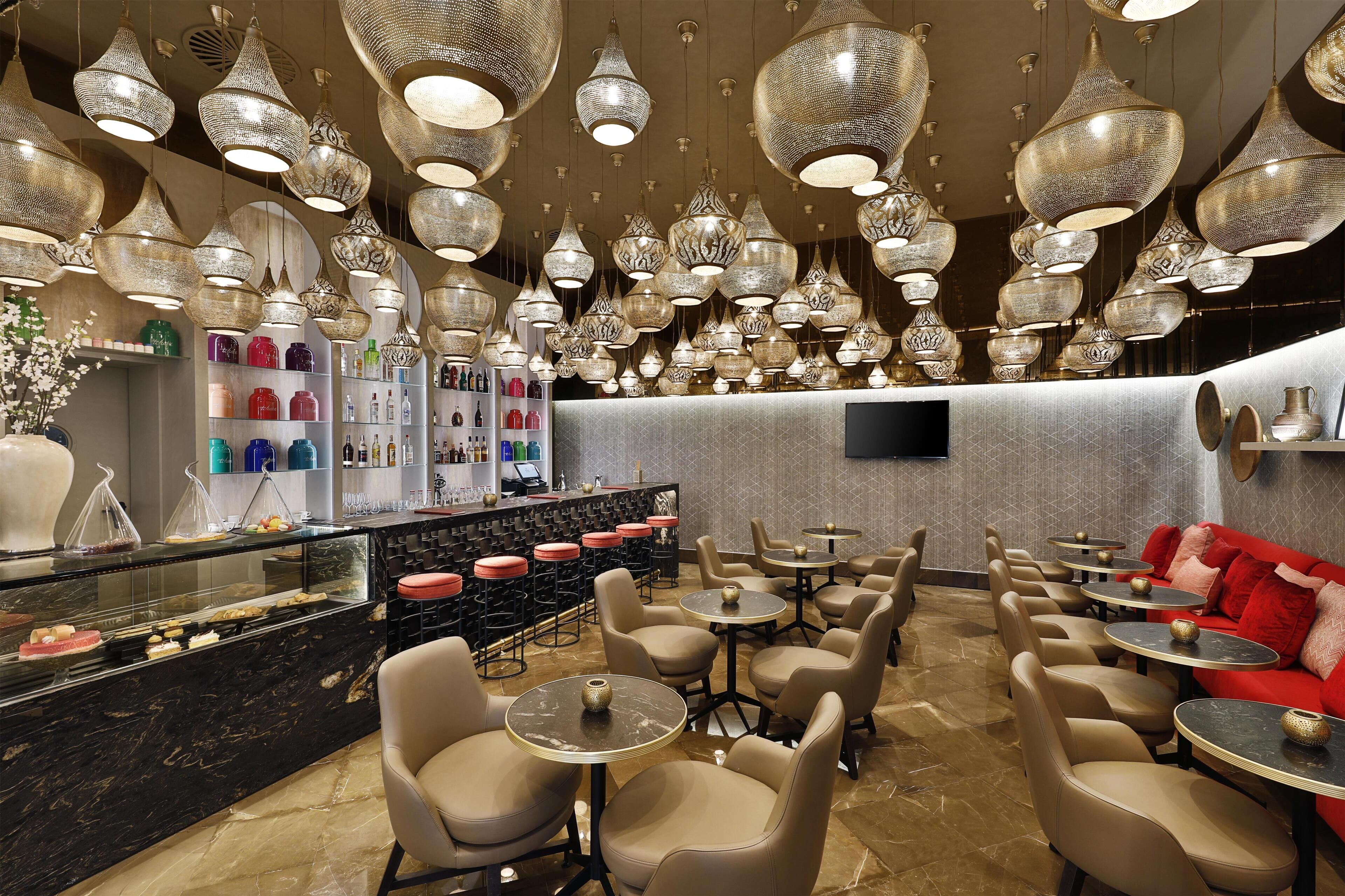 A restaurant with multiple seating areas, a bar, and decorative hanging lights.