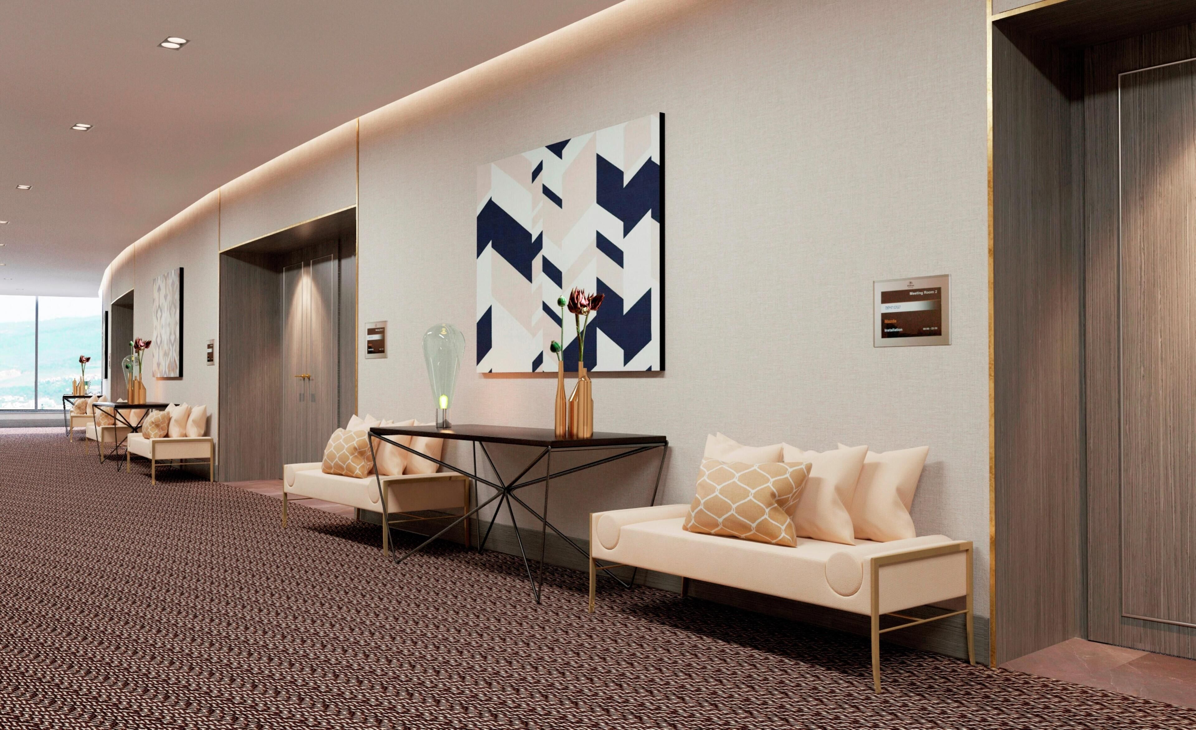 En hotellobby med en böjd vägg, sittgrupper och en stor, abstrakt målning.