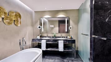 Casa de banho moderna com banheira, duas pias, um espelho grande e cabine de duche em vidro.