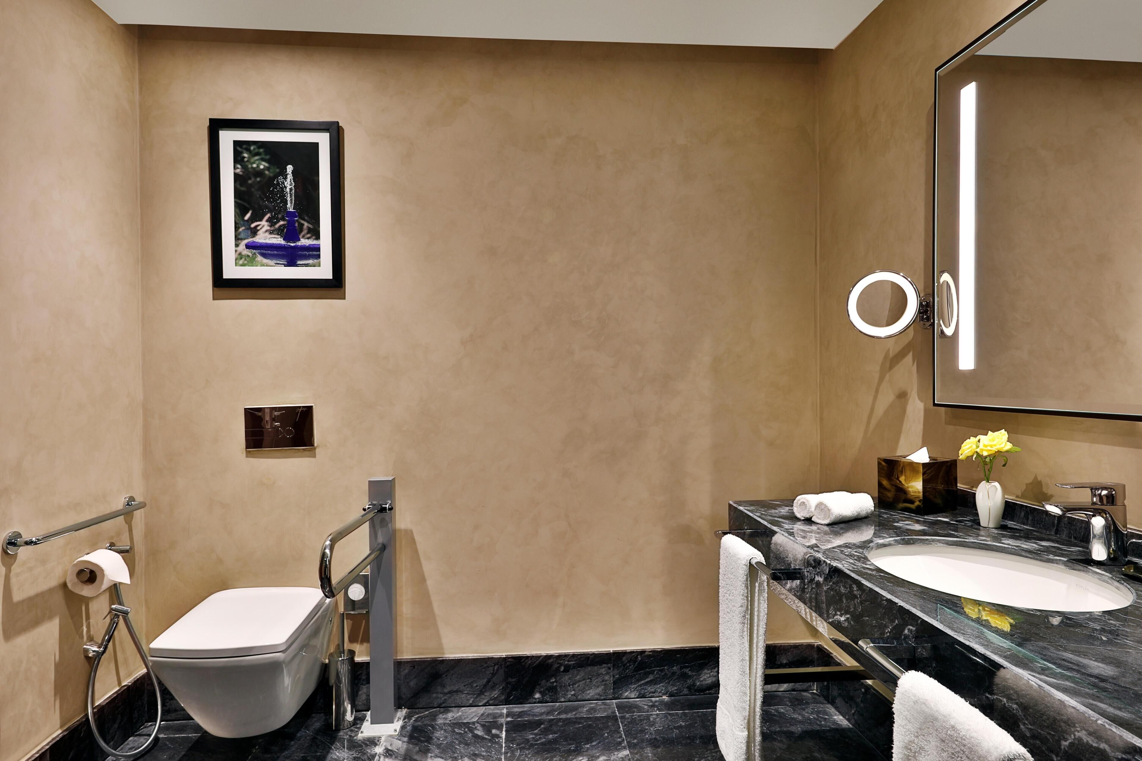 A modern bathroom with a toilet, bidet, vanity with a sink, and a large mirror.