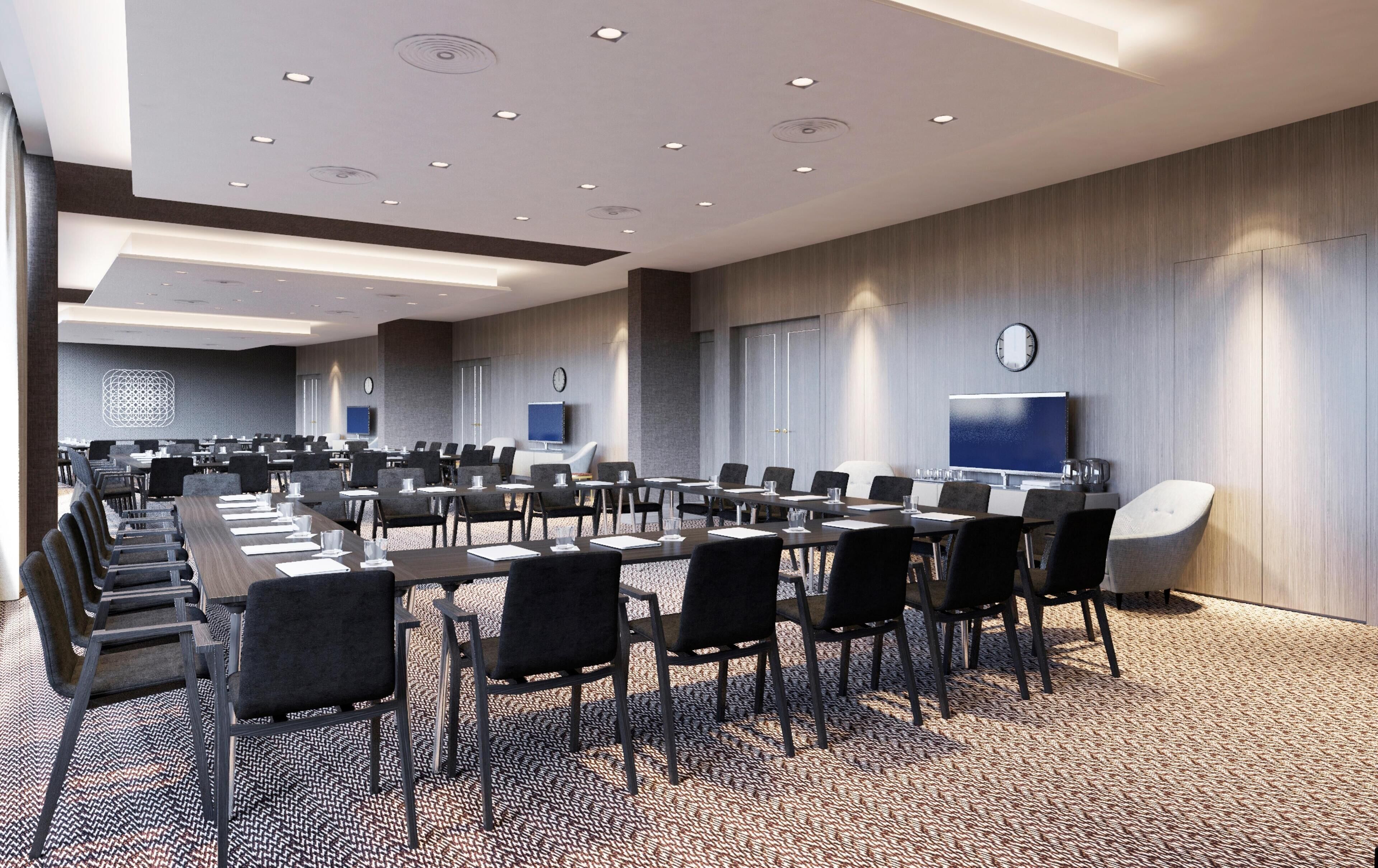 A conference room with multiple tables and chairs, a clock, and a flat-screen TV on the wall.
