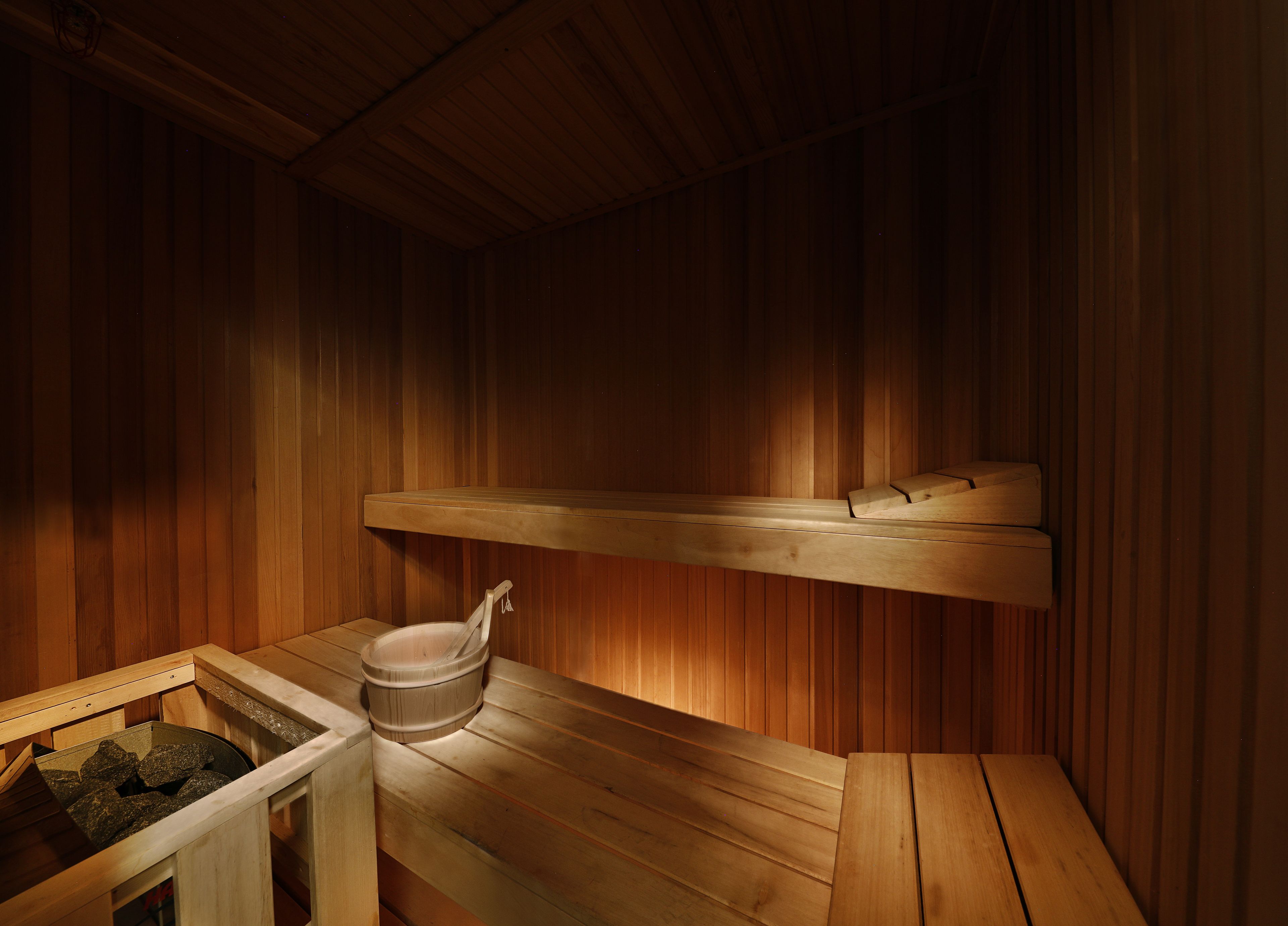 Una sauna con bancos de madera y una cuenca de piedra.