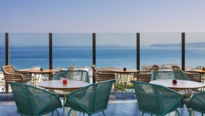 A terrace with tables and chairs overlooking the sea.