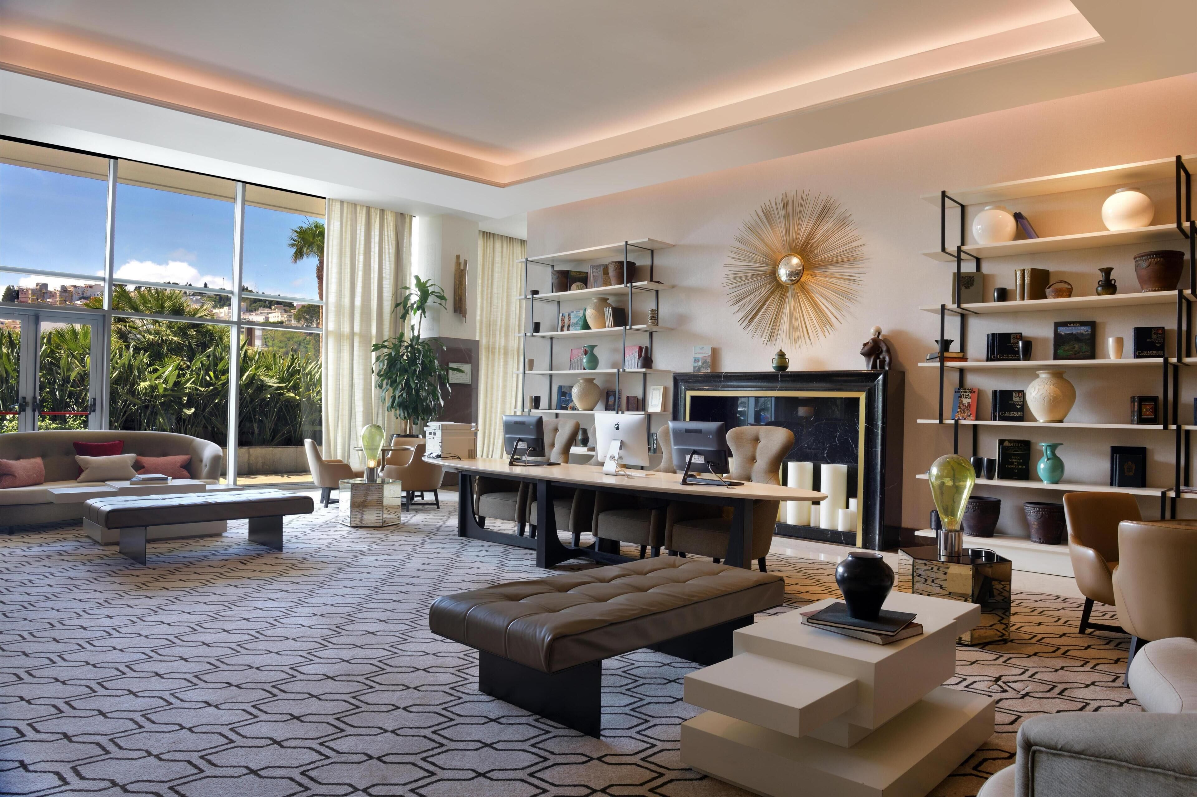 A modern living room with a large window, a fireplace, and a bookshelf.