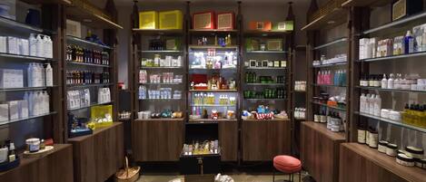 A well-organized store with shelves stocked with various products, a central display table, and a red stool.