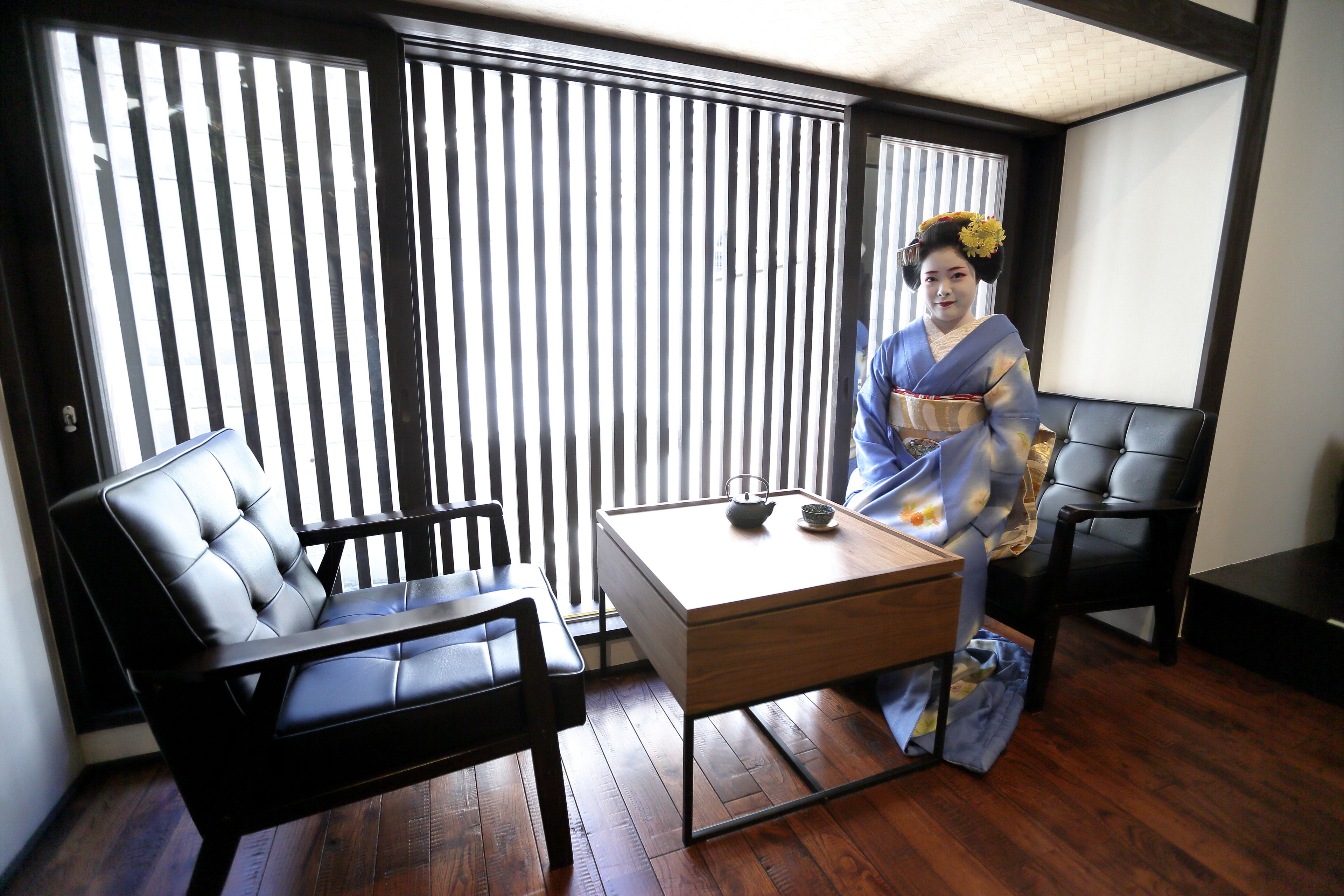 A traditional Japanese room with tatami flooring, a low table, and a sliding door with vertical blinds.