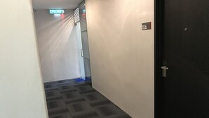 Un pasillo con piso alfombrado, una puerta con placa de número y un letrero que indica la dirección a la cocina.