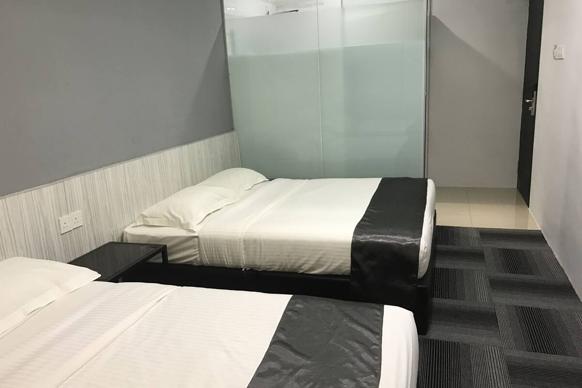 Ett hotellrum med två sängar, ett nattduksbord, en garderob och ett badrum.