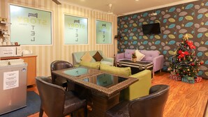 A hotel room with striped walls, a ceiling fan, a television, a Christmas tree, and a seating area with a table and chairs. - Hotel O Storytel (Kota Kinabalu)