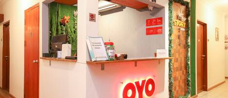 A reception desk with a sign reading "OYO HOTEL STORYTEL" and a "RECEPTION" sign above it.