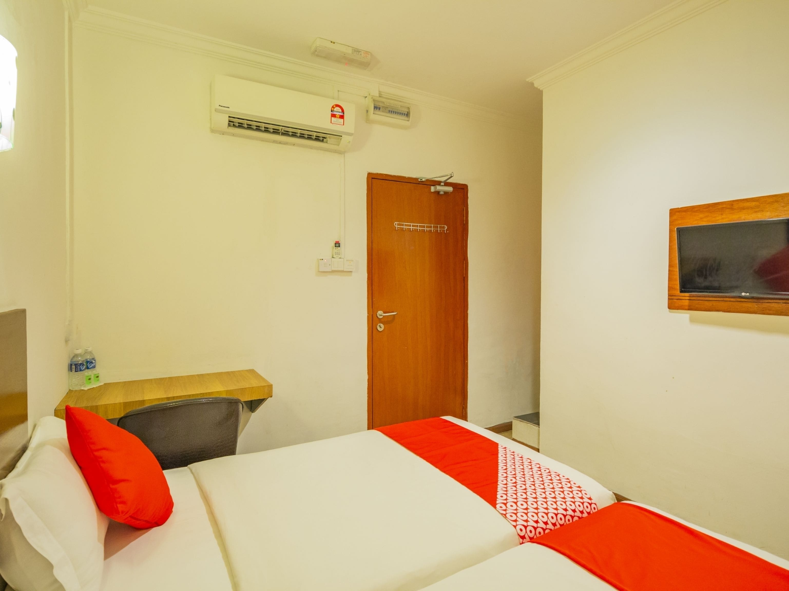 Une chambre d’hôtel équipée d’un lit, d’un bureau en bois, d’une télévision et d’un appareil de climatisation.