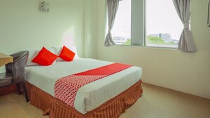 A hotel room with a bed, a chair, a window with curtains, and a view of buildings outside. - Hotel O Storytel (Kota Kinabalu)