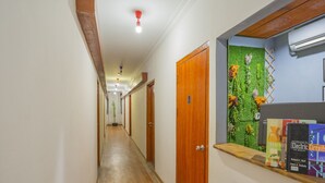 A hallway with wooden doors, a green wall with plants, and books on a shelf. - Hotel O Storytel (Kota Kinabalu)