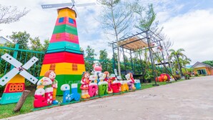 A colorful windmill and various whimsical sculptures along a pathway. - Samrong Garden Resort (Udon Thani)