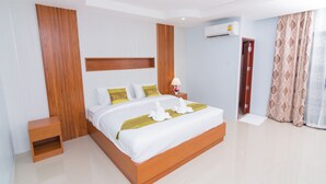 A modern hotel room with a large bed, wooden headboard, a nightstand, a wall-mounted air conditioner, and a door with a curtain. - Samrong Garden Resort (Udon Thani)