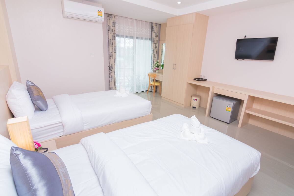 Una habitación de hotel con dos camas, televisión, escritorio y nevera pequeña.