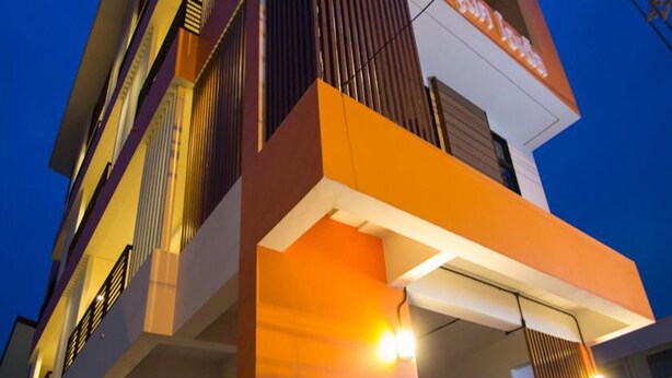 Un edificio de varios pisos con un diseño arquitectónico moderno, que cuenta con balcones y un llamativo esquema de color naranja y blanco.