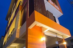 A multi-story building with a modern architectural design, featuring balconies and a prominent orange and white color scheme. - Bouquet Boutique Hotel (Udon Thani)