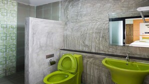 Un baño con inodoro y lavamanos verdes, y una pared de mármol.