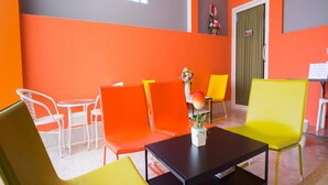 Una habitación con paredes anaranjadas, una mesa negra y sillas amarillas y anaranjadas.