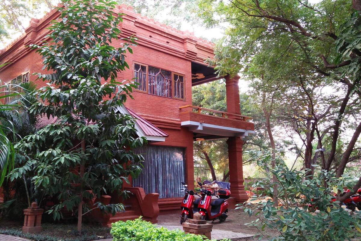 A red brick building with a covered porch and two red scooters parked in front.