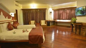 A hotel room with a large bed, a desk, a chair, a television, and a window with curtains. - Ananta Bagan Hotel (Nyaung-U)