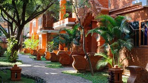 A courtyard with brick buildings, palm trees, and a paved walkway.