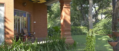 A brick building with a covered porch, a large column, and potted plants.