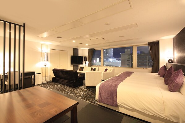 Una habitación de hotel con una cama grande, un escritorio, un sofá y un televisor.