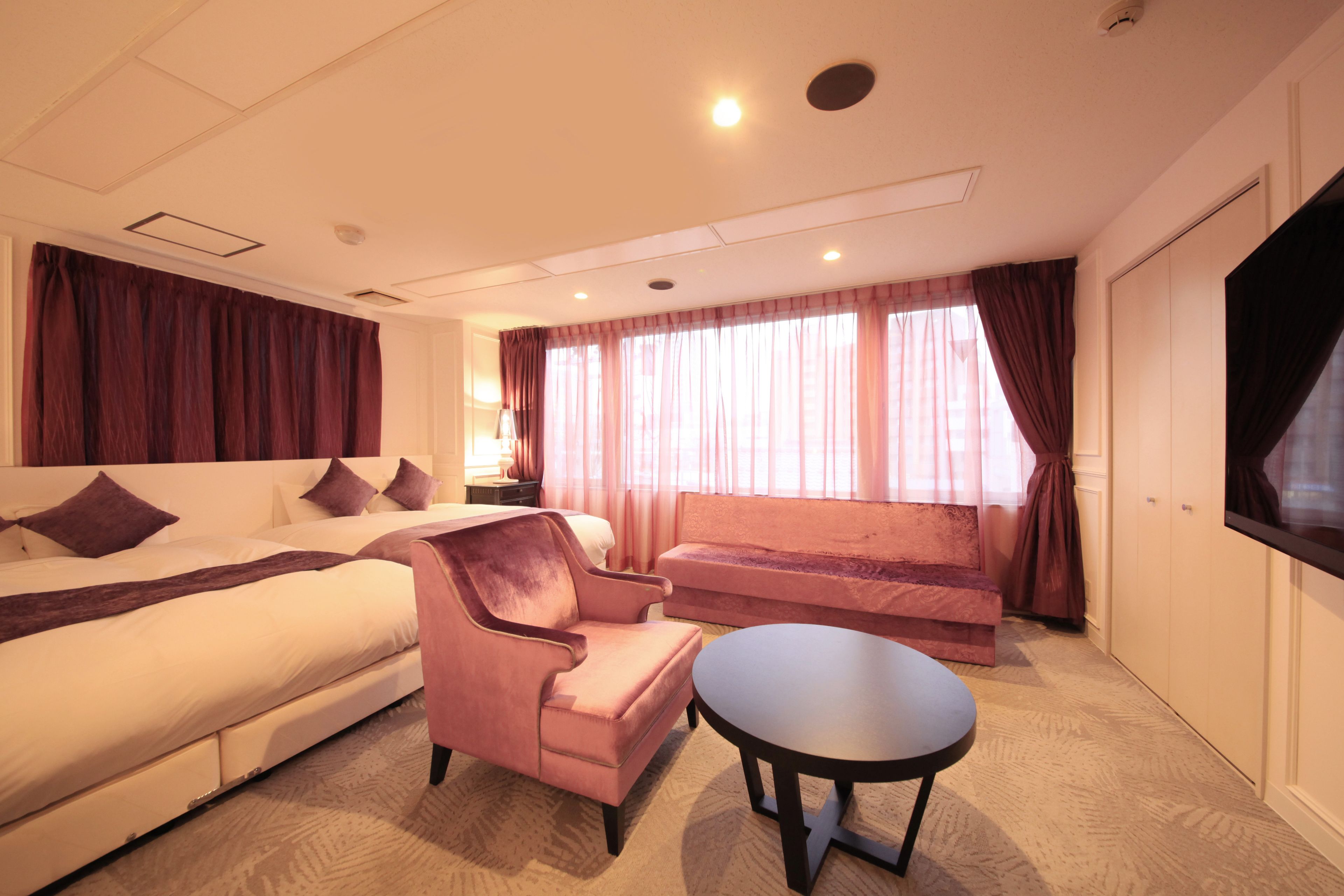 Ein Hotelzimmer mit einem Bett, einer Couch, einem Sessel, einem kleinen Tisch und einem Fernseher.