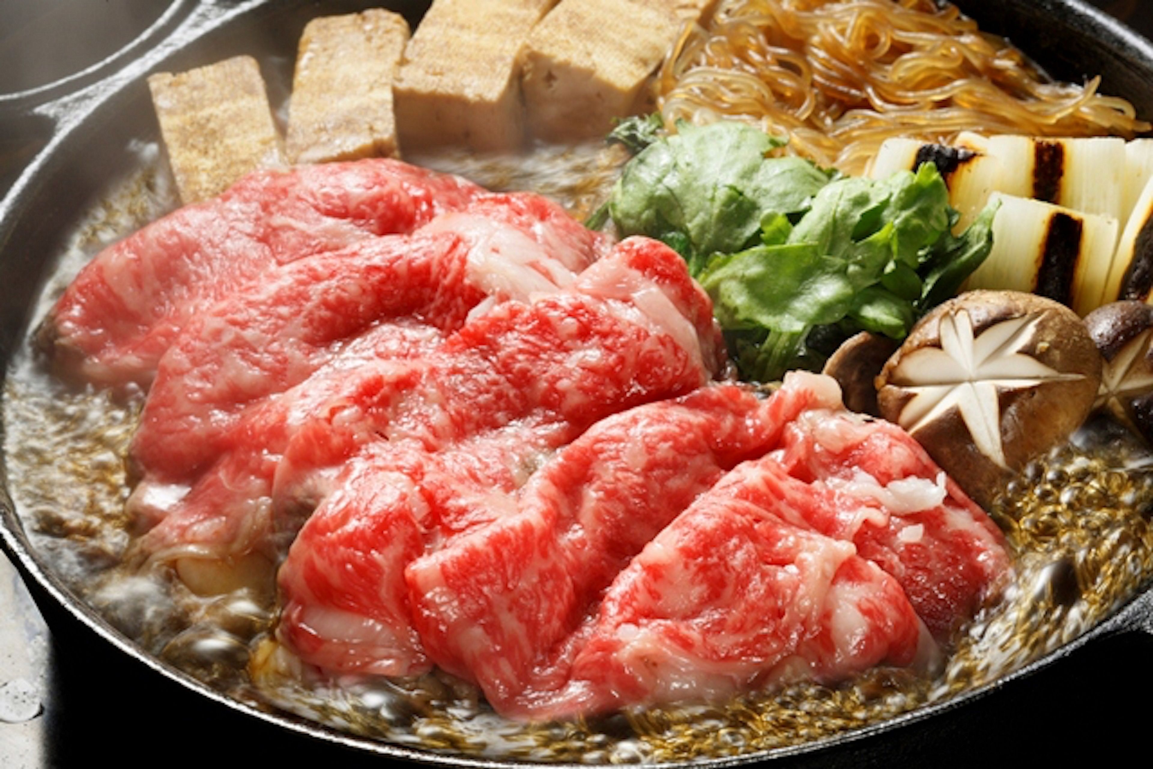 Una olla caliente con diversos ingredientes, incluyendo carne, verduras y tofu.