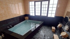 A bathroom with a bathtub, a window, and a shower area. - Utopia Naeba (Yuzawa)